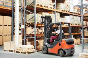 Worker driving forklift in warehouse